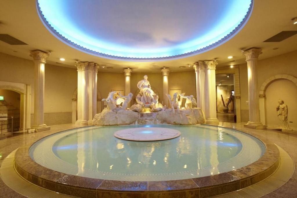 a large pool in the middle of a building with a fountain at Spa World HOTEL&RESORT in Osaka