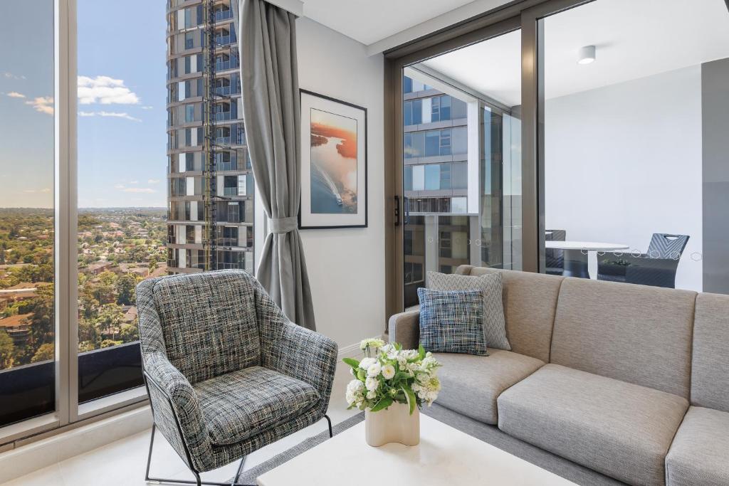 a living room with a couch and chairs and large windows at Meriton Suites George Street, Parramatta in Sydney