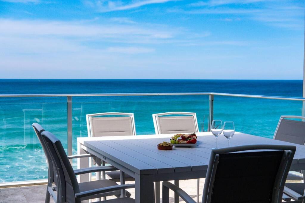 una mesa y sillas en un balcón con vistas al océano en Paradise Penthouse - Beach Front Style and Luxury, en The Entrance