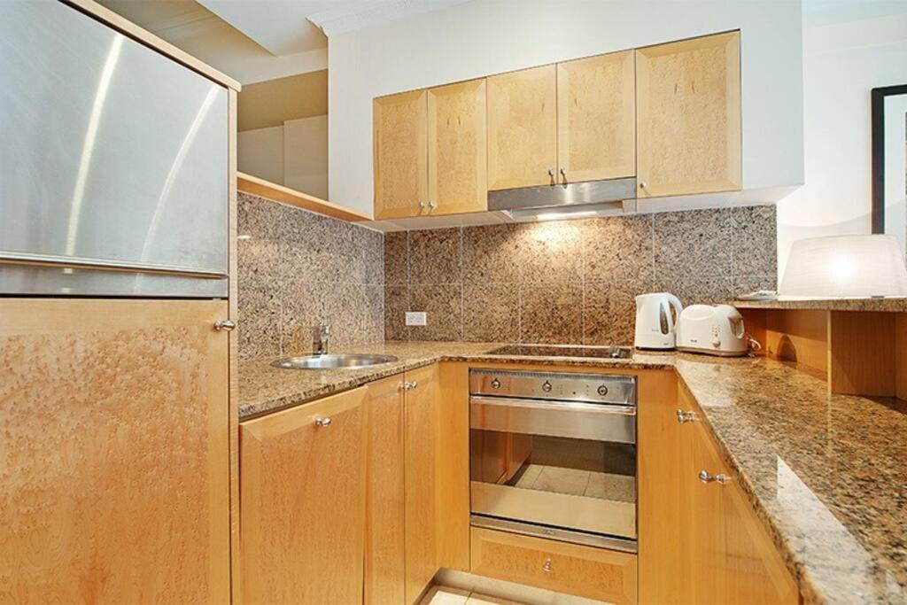 a kitchen with wooden cabinets and a stove top oven at Fantastic location - apartment in Sydney CBD BON02617 in Sydney