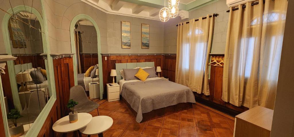 um quarto com uma cama e duas mesas e um espelho em Hotel Voila Londres em Santiago