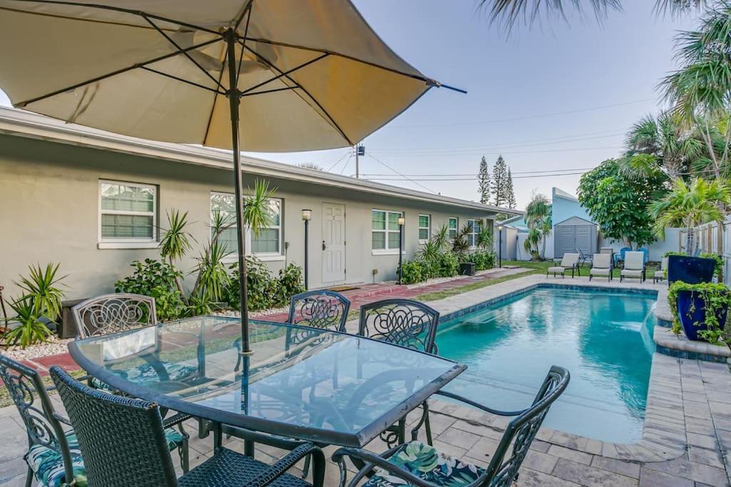 una mesa con sillas y una sombrilla junto a la piscina en Entire Villa - Sleeps 16 Heated Pool East of A1A, en Cocoa Beach