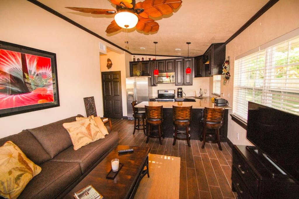a living room with a couch and a kitchen at Tahitian Cottage - Heated Pool Walk to the Beach in Cocoa Beach
