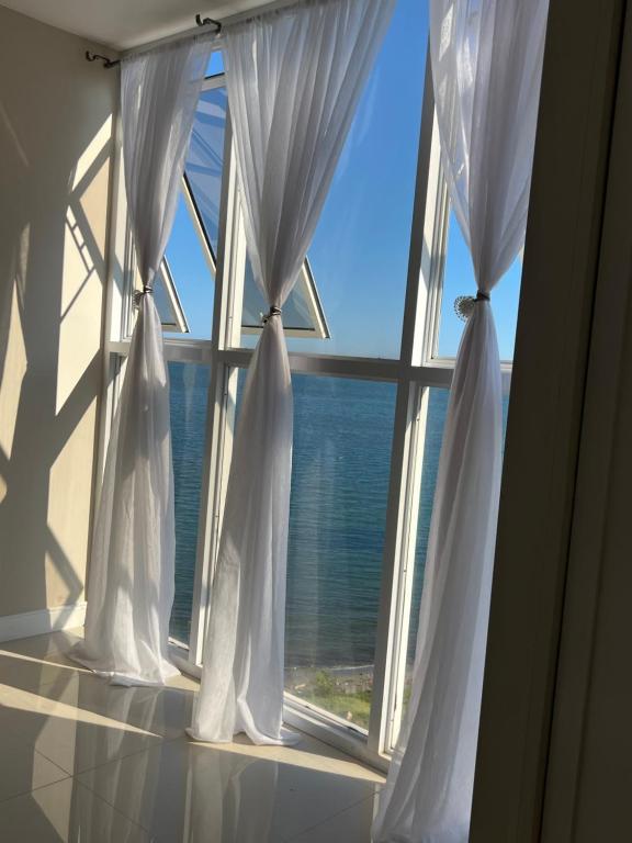 una ventana con cortinas blancas frente al océano en Large Luxurious Beach Front 1 Bedroom at Bayfront Villa en Portmore