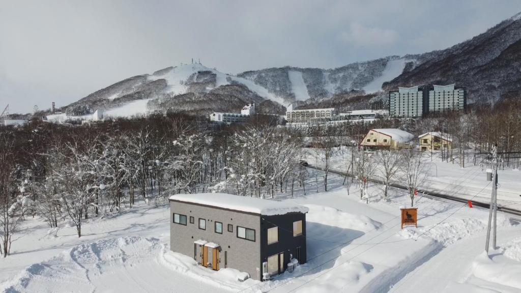 un edificio en la nieve con una montaña en el fondo en WaPura Rusutsu, en Rusutsu