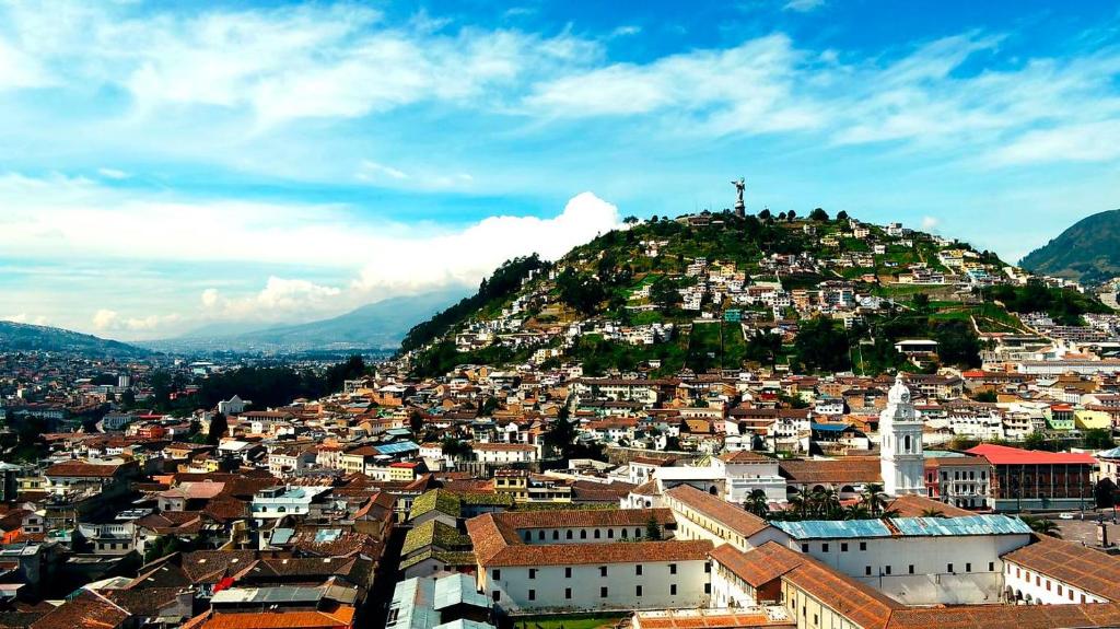 vistas a una ciudad con una cruz en una colina en Hostal History, en Quito