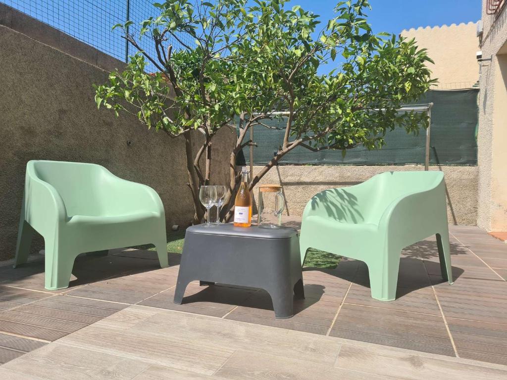 2 chaises vertes et une table avec un arbre dans l'établissement Appartement calme avec terrasse - 2 chambres, 4 pers, proche plage et randonnées, Banyuls-sur-Mer - FR-1-225C-95, à Banyuls-sur-Mer