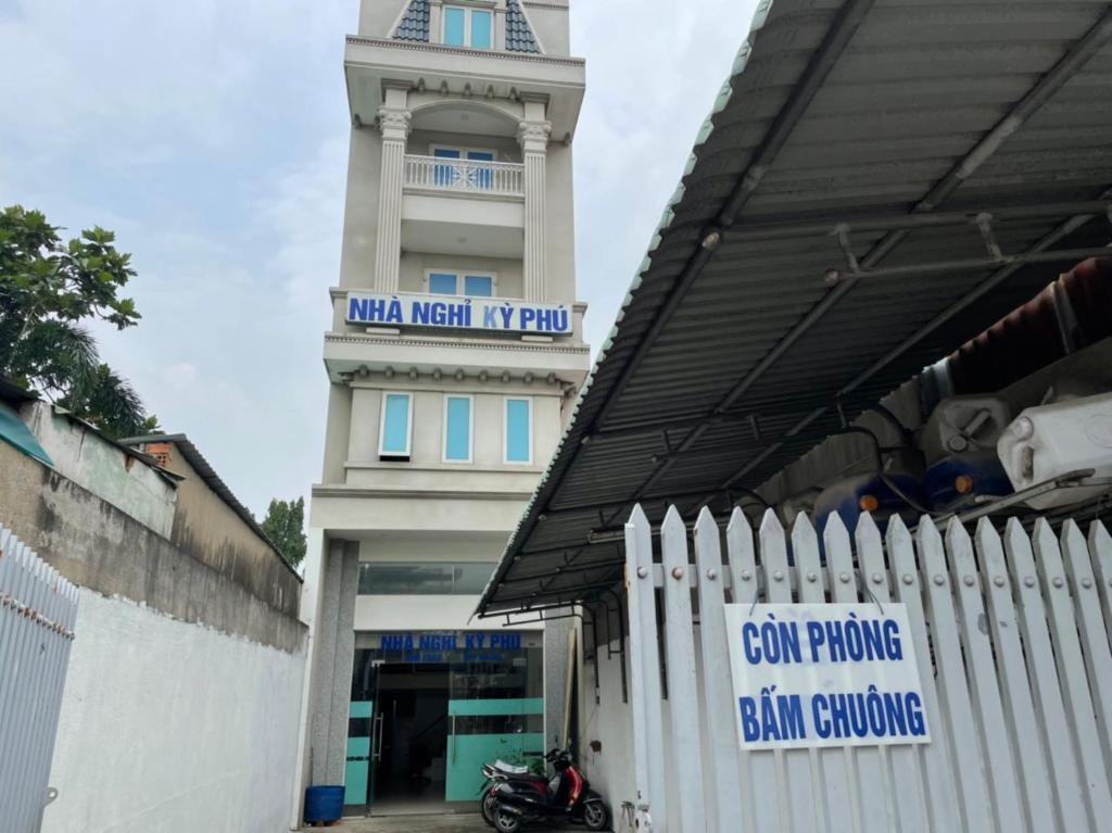 een wit hek voor een gebouw met een klokkentoren bij Ky Phu in Thuan An