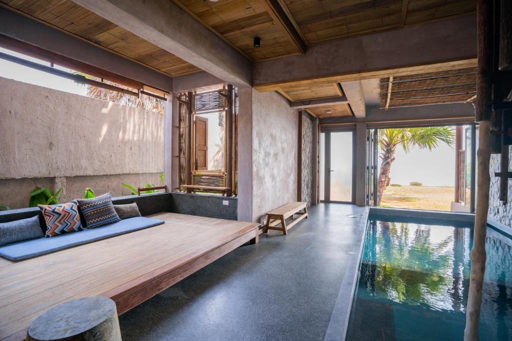 Habitación con piscina y banco de madera junto a una mesa. en LA A NATU Pranburi, en Sam Roi Yot