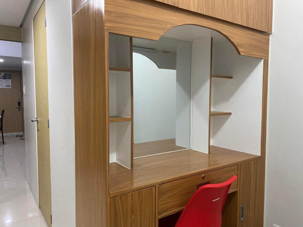 d'une armoire en bois avec un miroir et une chaise rouge. dans l'établissement Jeffrey Paradero - Fern Residence Tower 4, à Manille