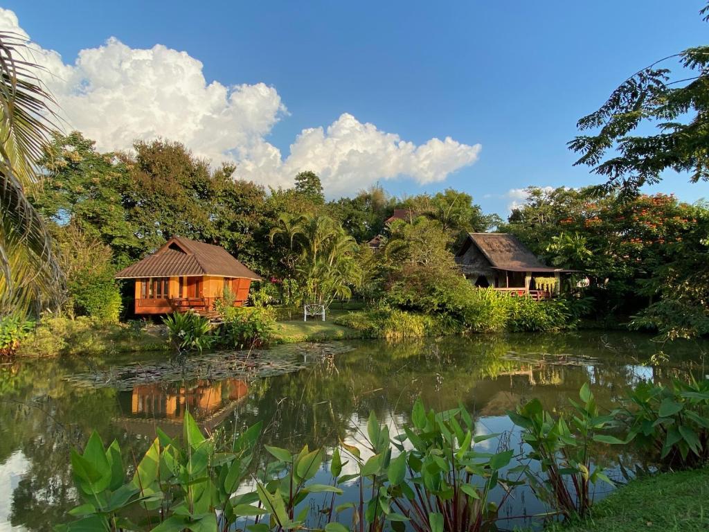 a couple of houses next to a body of water at Pura Vida Pai Resort in Pai