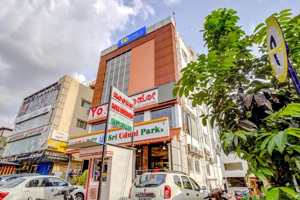 a street with cars parked in front of a building at FabHotel Sri Udupi Park in Bengaluru
