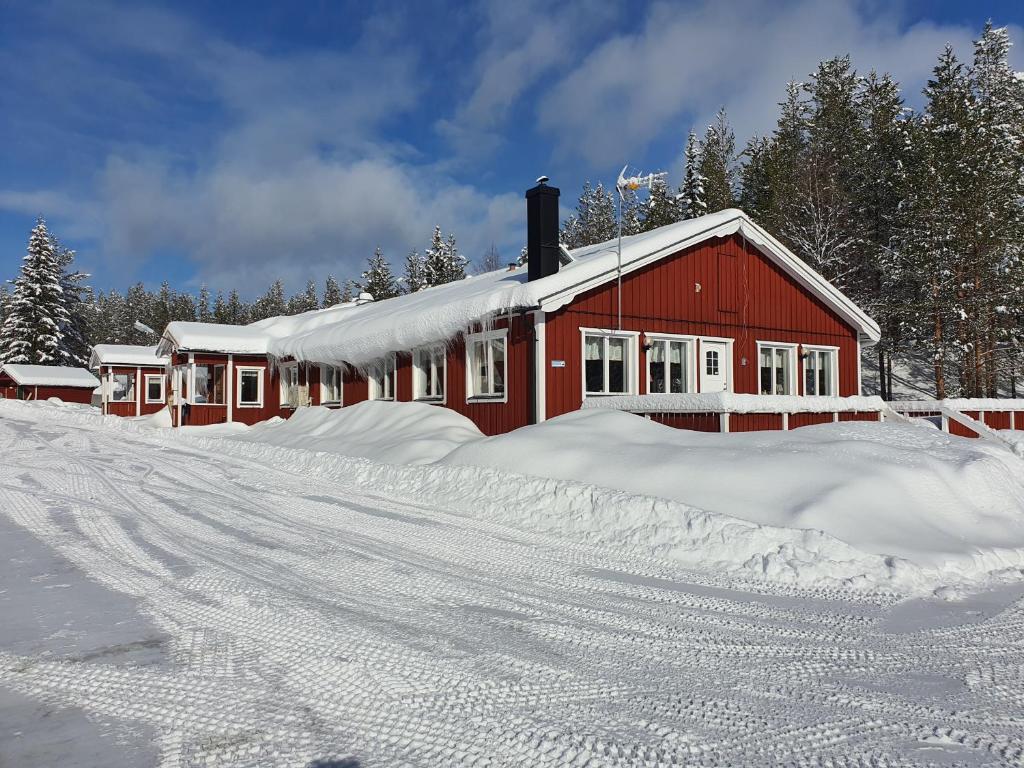una casa roja está cubierta de nieve en Fulufjällsgården en Mörkret