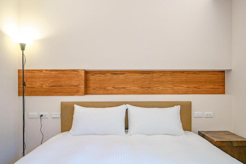 a bedroom with a white bed with a wooden headboard at 東風雅舍 in Hualien City