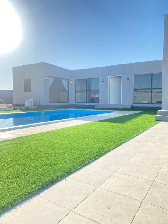 une maison avec une piscine et de l'herbe verte dans l'établissement شاليه ريفان, à Umm Lajj