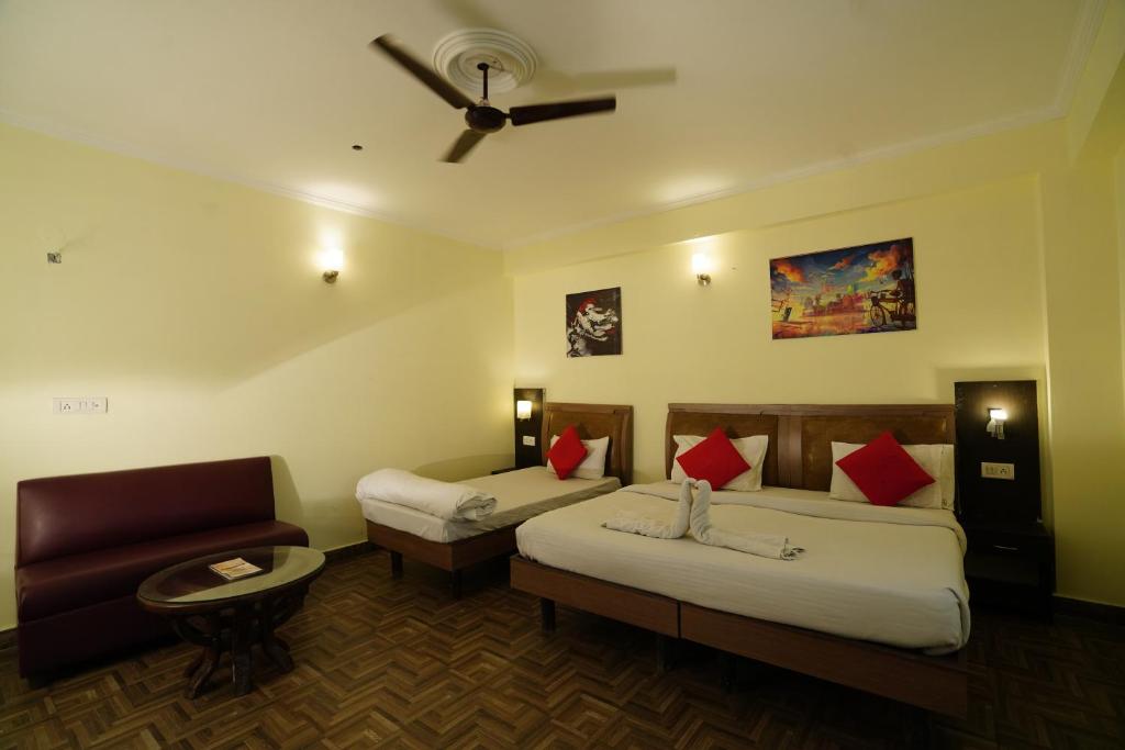 a hotel room with two beds and a couch at Hotel Gaurab Near Railway Station in Dehradun