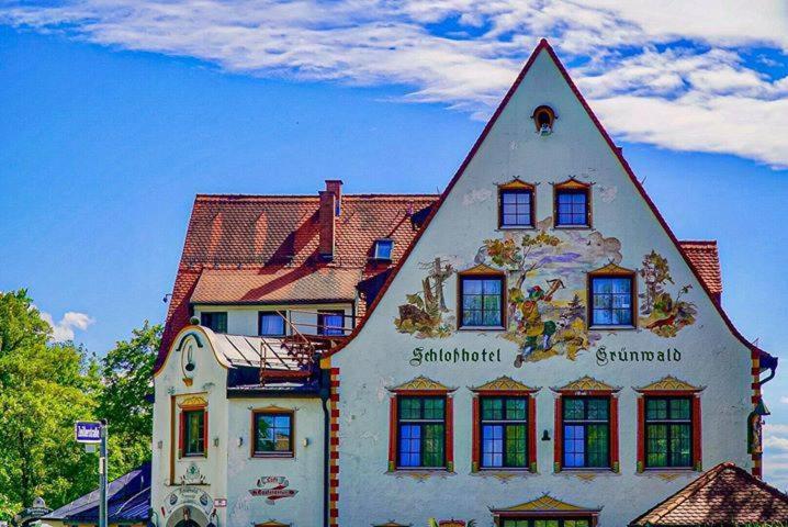 ein weißes Gebäude mit spitzem Dach in der Unterkunft Schlosshotel Grünwald in Grünwald