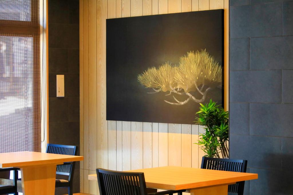 a restaurant with two tables and chairs and a picture on the wall at Waqoo Naritasanmonzen in Narita