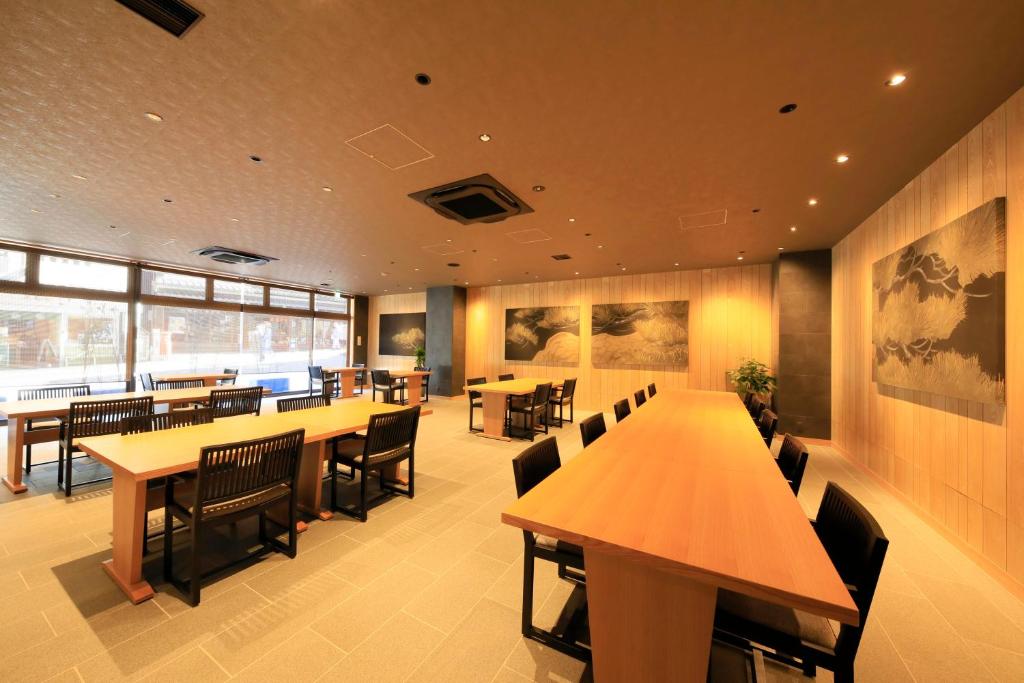 a restaurant with wooden tables and chairs and windows at Waqoo Naritasanmonzen in Narita