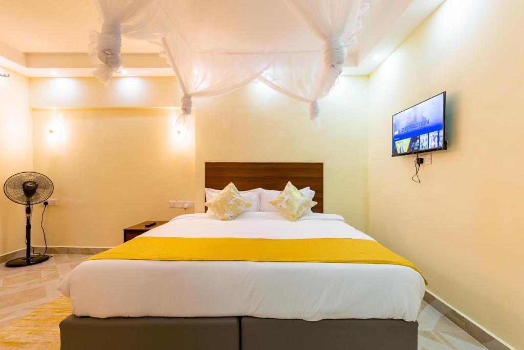 una camera da letto con un grande letto con una coperta gialla di Marrkson Suites a Nairobi