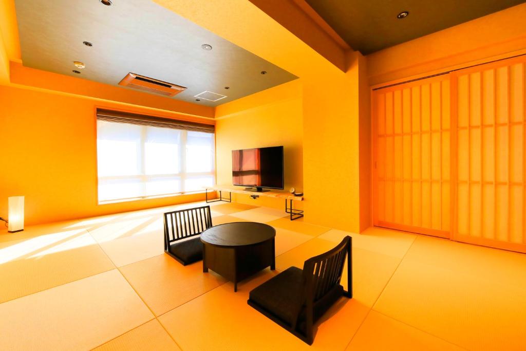 a room with a table and two chairs and a television at Waqoo Naritasanmonzen in Narita