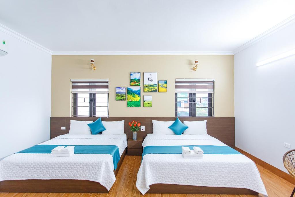 2 camas en una habitación de color blanco y azul en Blue Eyes Hotel, en Văn Lâm