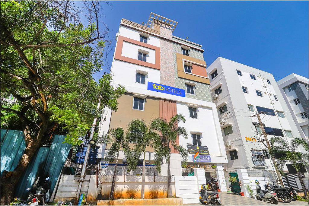 a tall white building with a blue sign on it at FabHotel Broholic in Hyderabad