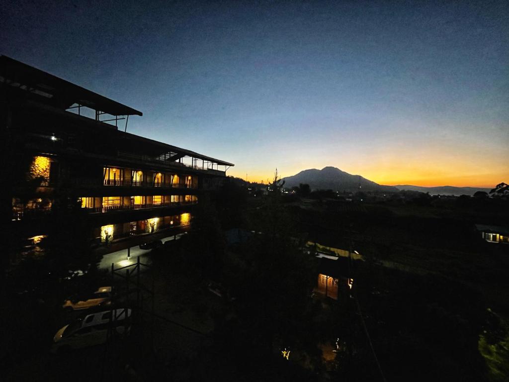 a building at sunset with a mountain in the background at Hotel Kalang Ulu in Berastagi