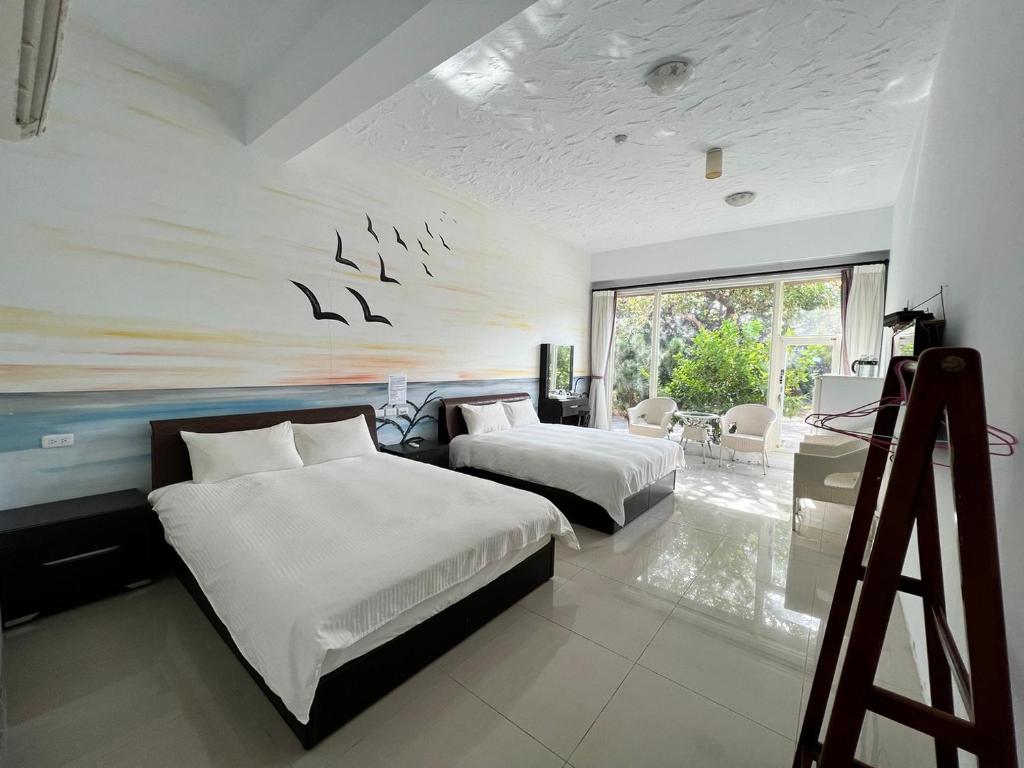 un dormitorio con 2 camas y una pared con pájaros. en Mang Yi Zhan Inn en Kenting