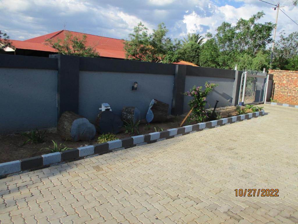 a blue fence with rocks and a yard at PS GOOD TIME GUEST HOUSE in Klerksdorp