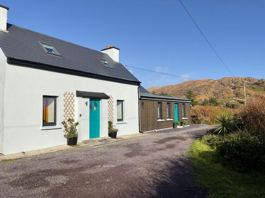 a white house with a blue door on a street at Wild Wild West Holiday Cottages in Castletownbere