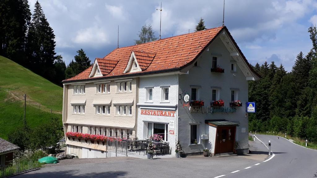 ein weißes Gebäude mit orangefarbenem Dach auf einer Straße in der Unterkunft Schwellbrunn,Ferienwohnung mit Säntissicht in Schwellbrunn