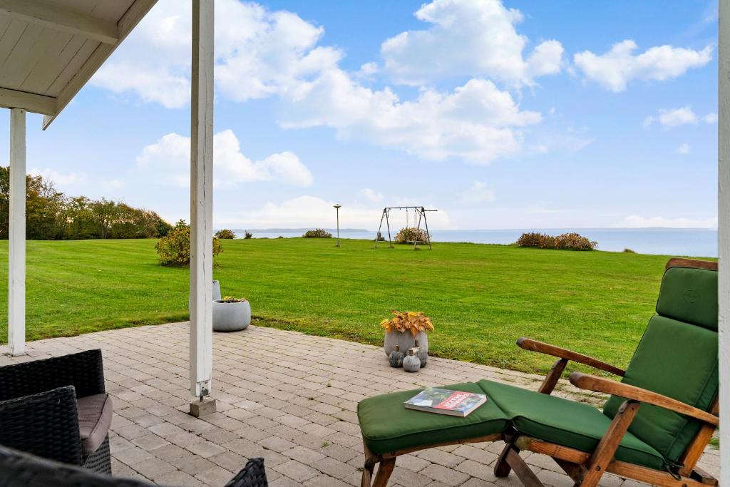 eine Terrasse mit einem grünen Stuhl und einem Spielplatz in der Unterkunft Remarkable 2-Bed Beach House 12J in Brenderup