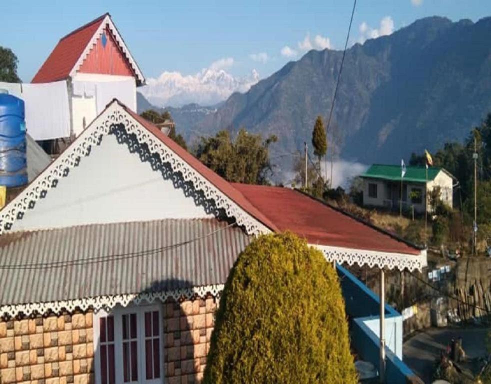 una casa con techo rojo con montañas al fondo en Mountain View Home Stay by StayApart, en Darjeeling