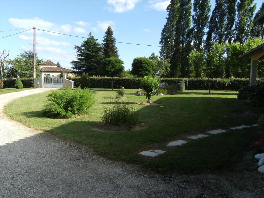 a garden with grass and bushes and a house at La maison de Campagne in Campagne-dʼArmagnac