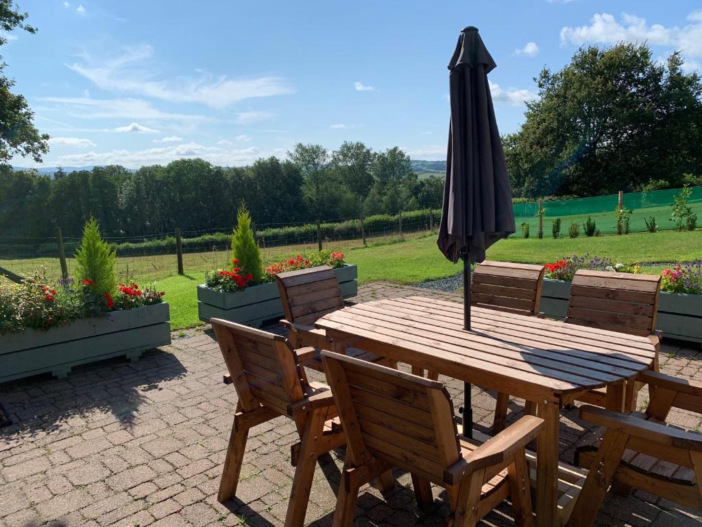 a wooden table and chairs with an umbrella on a patio at The Longhouse, Brecon Beacons (King & Twin) in Brecon