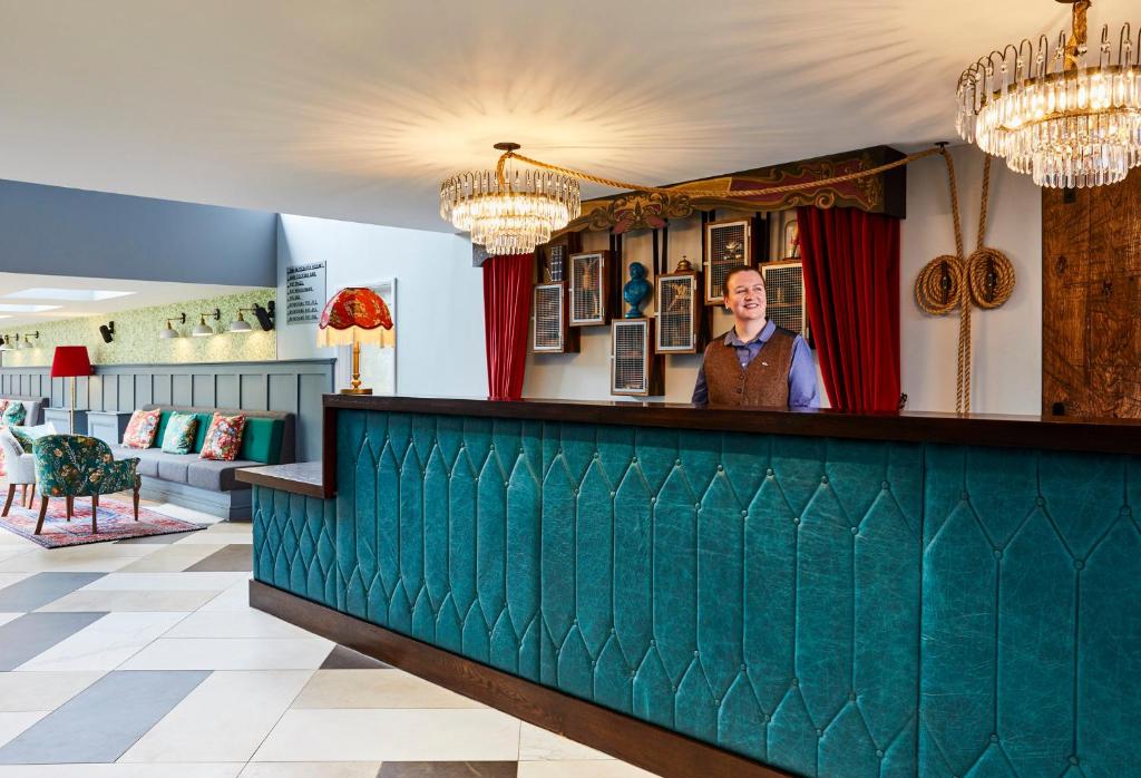 un homme debout derrière le bar d'un restaurant dans l'établissement Hotel Indigo - Stratford Upon Avon, an IHG Hotel, à Stratford-upon-Avon
