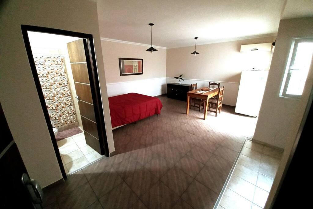 Un dormitorio con una cama roja y una mesa en una habitación en Hermoso monoambiente en complejo residencial. en Godoy Cruz