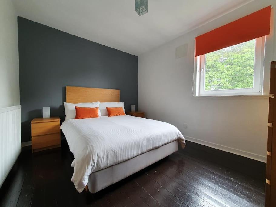 een slaapkamer met een bed met oranje kussens en een raam bij 2 Bedroom, free parking & Netflix near hospitals in Aberdeen