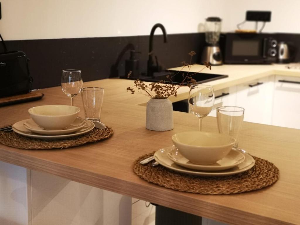 drewniany stół z dwoma płytami i okularami w obiekcie Oasis de 42 m2 I Cosy I Cœur de ville I Lit 160x200 w mieście Vaison-la-Romaine