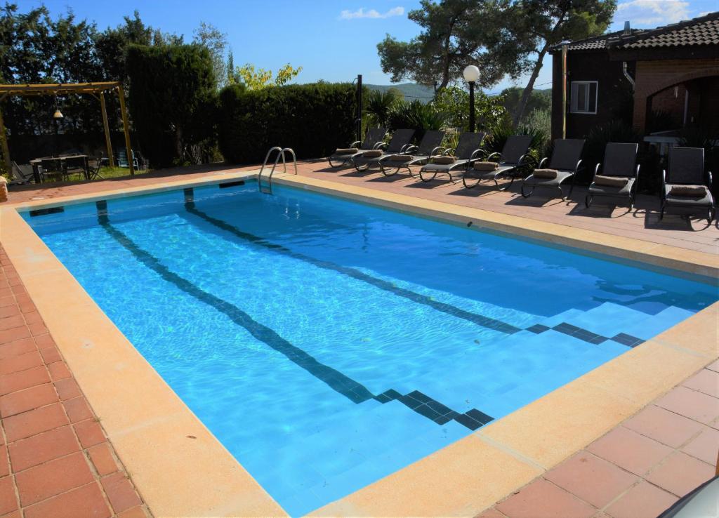 a large swimming pool with chairs and blue water at Villa Sitges Soledad 15 minutes drive from Sitges XXL swimming pool 12 p in Olivella