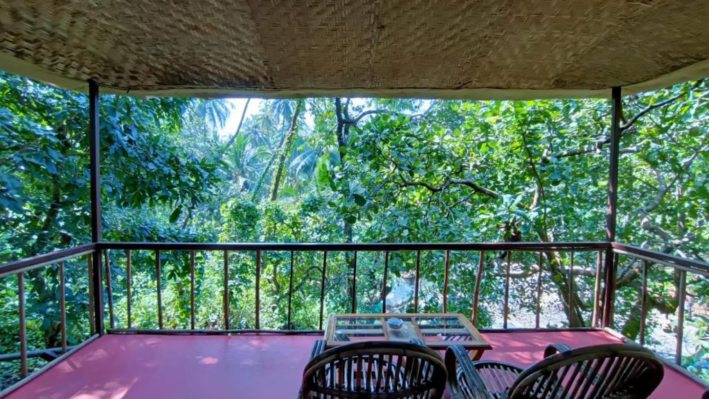 a screened in porch with two chairs and a table at Samyama Retreat in Cola