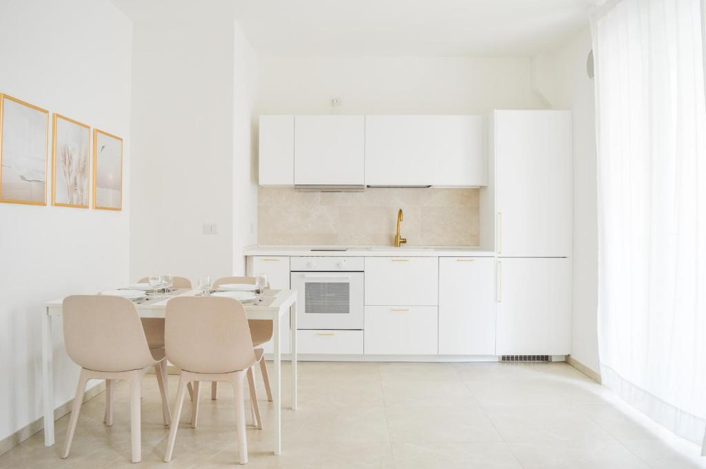 una cucina con armadi bianchi, tavolo e sedie di Homiday - Residenza Caravelle a Pineto