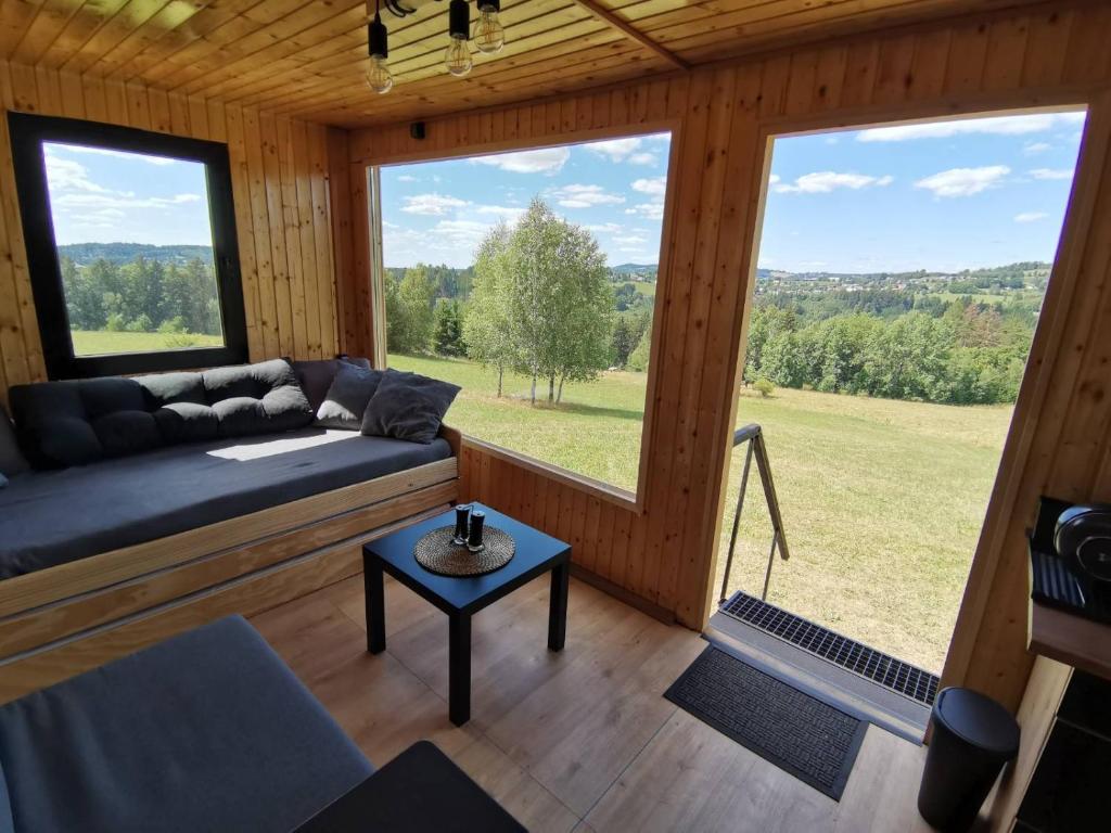 a living room with a couch and large windows at Zážitkový pobyt uprostřed přírody in Železný Brod