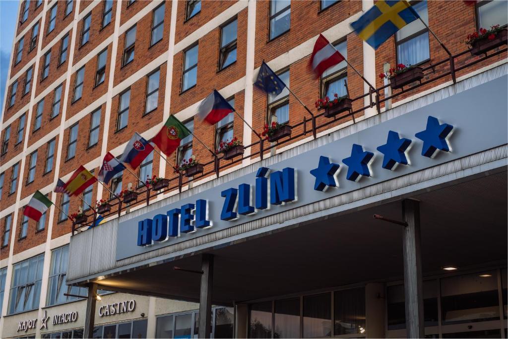 un edificio con un cartel para un hotel con banderas. en Interhotel Zlín en Zlín