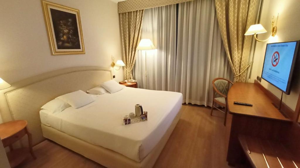 um quarto de hotel com uma grande cama branca e uma secretária em Best Western Hotel Globus City em Forlì