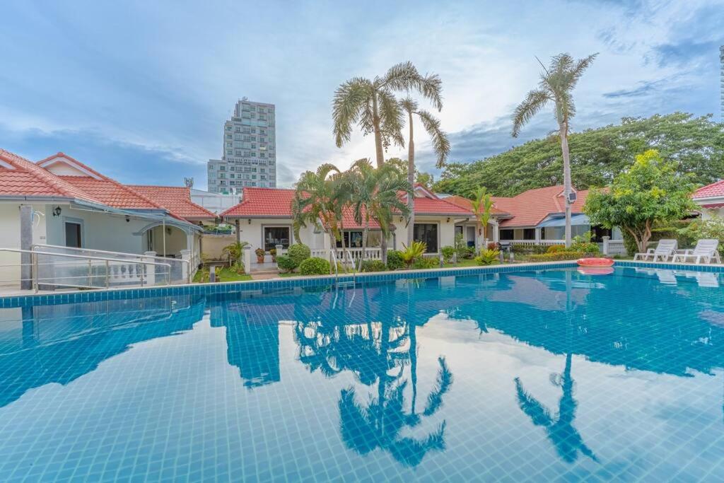 une grande piscine avec des palmiers et un bâtiment dans l'établissement Resort 5-3BR Huge Pool, BBQ, 300m-Beach, 8 mins to Walking Street, à Pattaya (sud)
