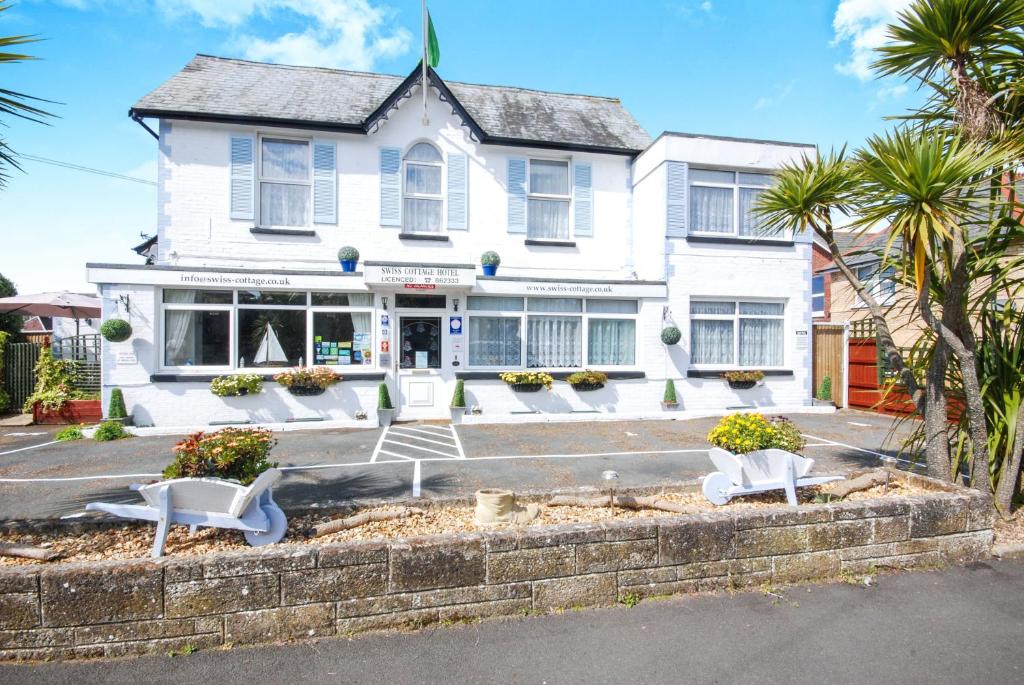 a white house with two white chairs in front of it at The Swiss Cottage, Shanklin in Shanklin