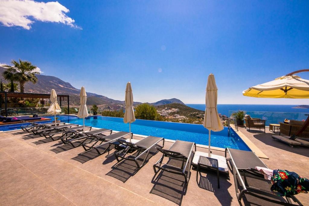 a swimming pool with lounge chairs and umbrellas at Villa Lapis - Kalkan Villa in Kas