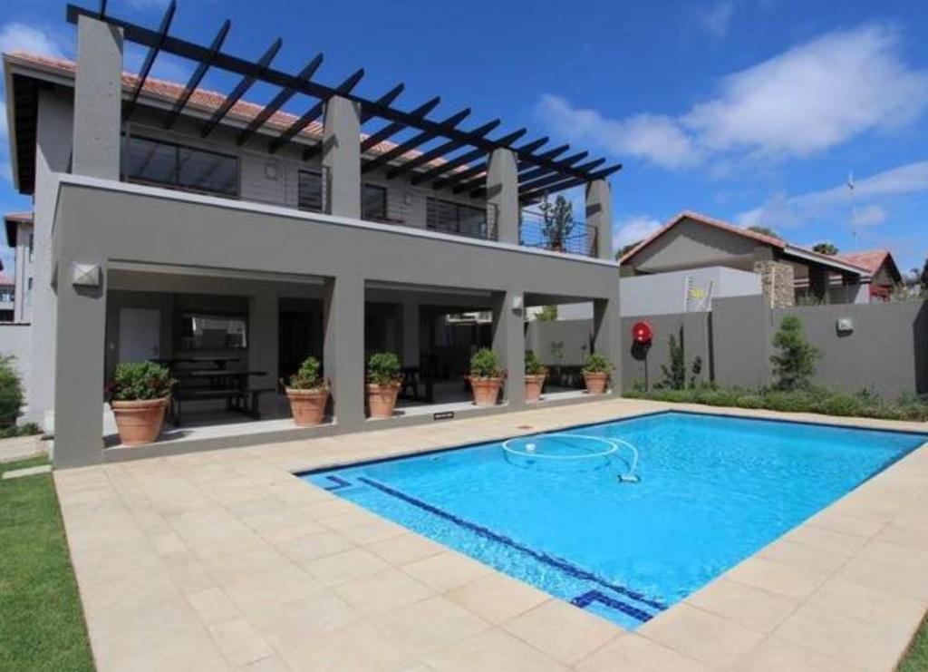 a house with a swimming pool in front of a house at Lovely, Modern, Contemporary 1 Bedroom Apartment. in Sandton
